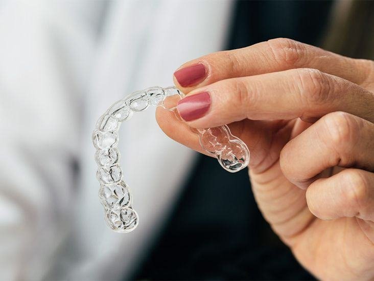 Hand holding a clear Invisalign aligner