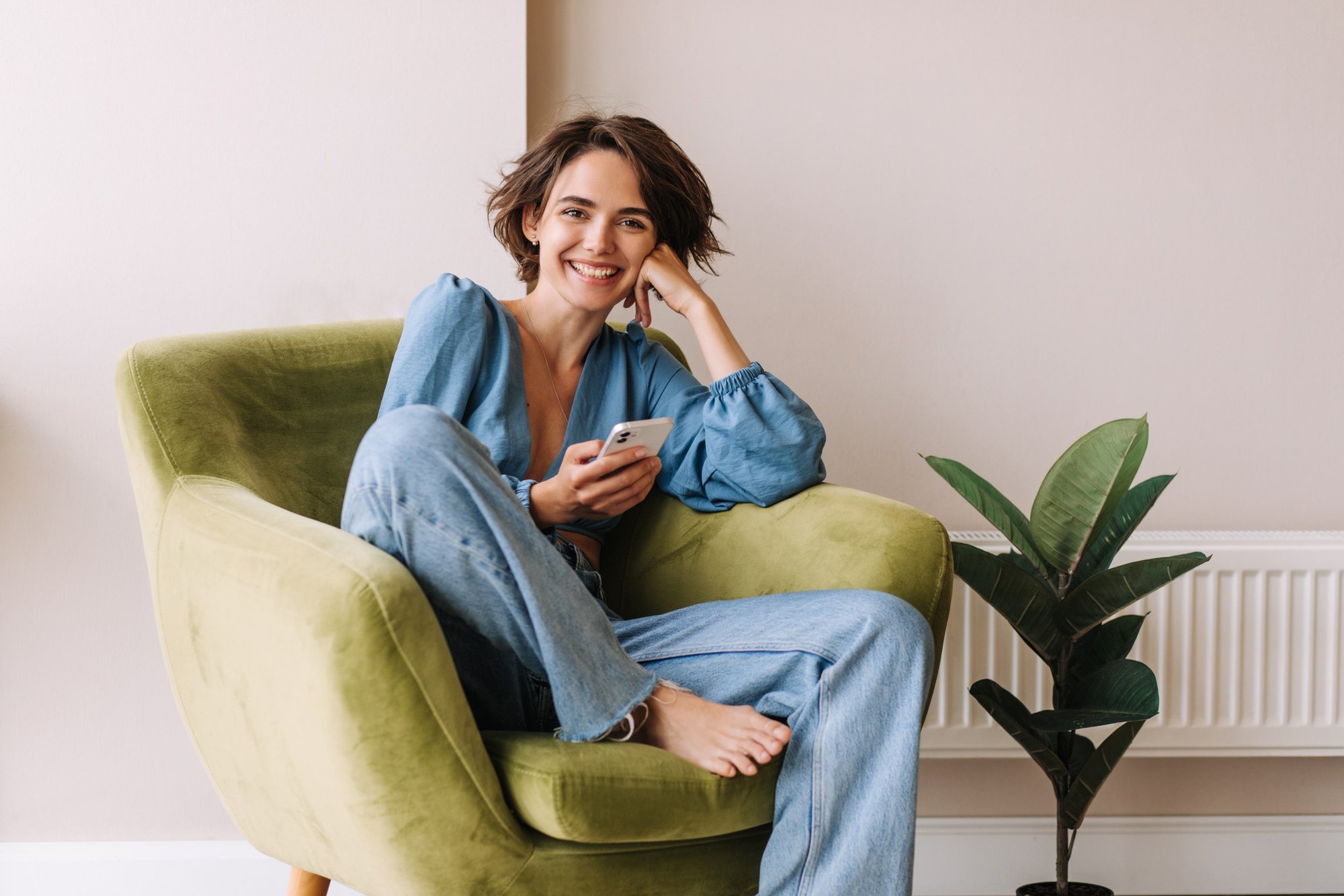 Relaxed, smiling woman sitting in a green armchair at home