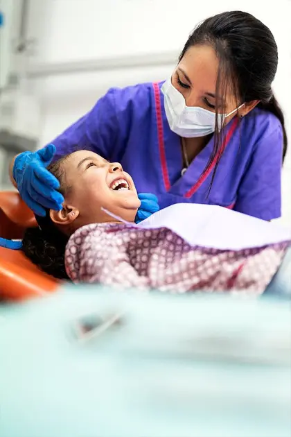 Dentist treating a smiling young child in the dental chair