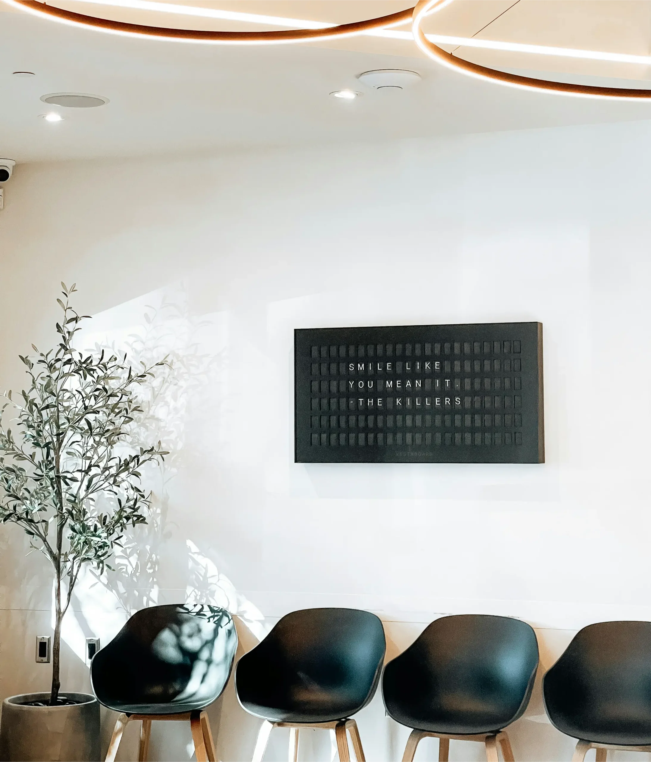 Waiting area with black chairs and a wall-mounted screen
