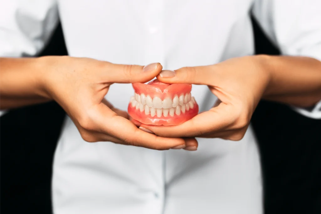Hands holding a full set of dentures