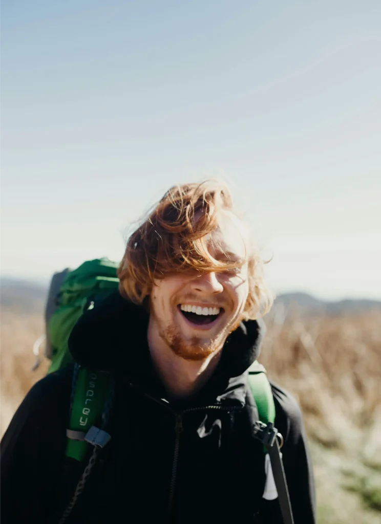 Young man with curly hair laughing outdoors